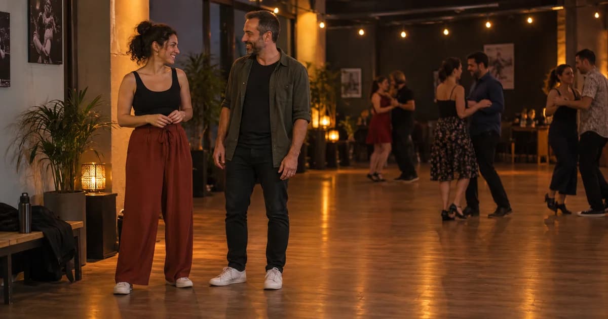 Two dancers taking a relaxed pause beside a social dance floor.